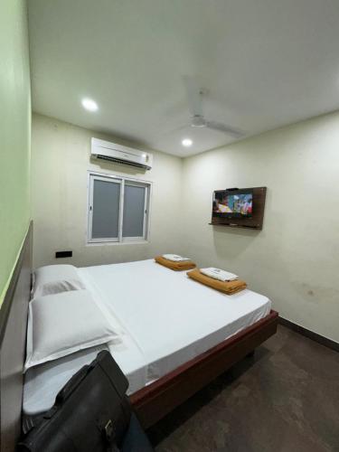 a bedroom with a large bed with a tv on the wall at Sangeetha Business Hotel in Chennai