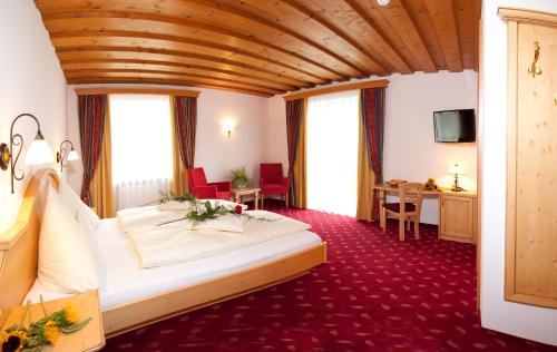 a hotel room with a large bed and a desk at Frühstückshotel Birkenhof in Rauris