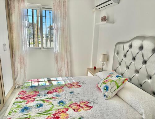 a bedroom with a bed with a floral quilt on it at Refugio Costero Tu Hogar vistas al Mar con Parking in Calahonda