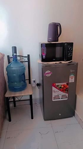 a microwave on top of a refrigerator next to a chair at Mombasa comfy studio in Mombasa
