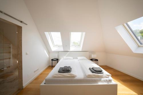 een witte slaapkamer met een bed op de zolder bij Luxury Penthouse Schönbrunn in Wenen