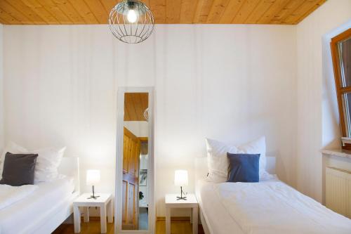 ein weißes Schlafzimmer mit 2 Betten und einem Spiegel in der Unterkunft Schönauer Hof - Wohnung Max Josef in Passau