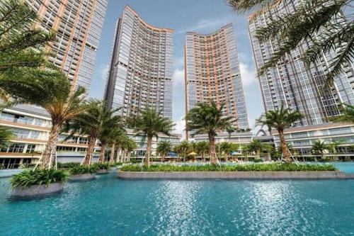 a pool with palm trees in front of tall buildings at gold coast pik BEACH ROOM 1br netflix wifi sofa bed in Jakarta