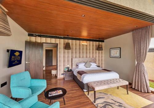 - une chambre avec un lit et deux chaises bleues dans l'établissement Aveda Suites at Aamby Valley city, à Lonavala