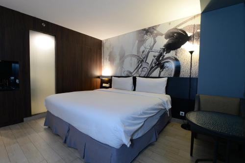 um quarto com uma grande cama branca e uma pintura de bicicleta na parede em HORU HOTEL MANGGA DUA SQUARE em Jacarta