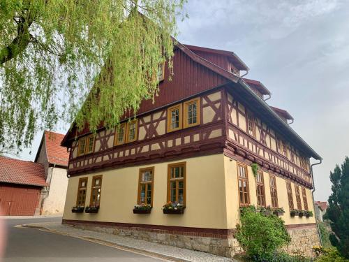 a house with a red roof and yellow windows at Landhotel Ruhepol - garni in Arnstadt