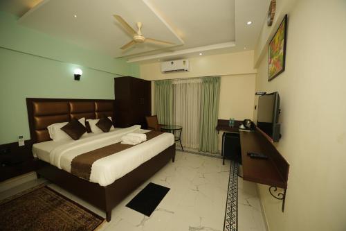 a bedroom with a bed and a desk and a ceiling fan at Saikiran Hotel in Mapusa