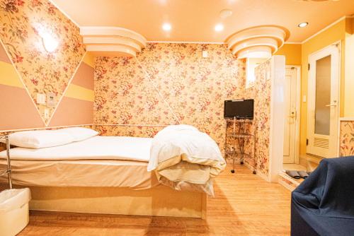 a bedroom with a bed and a tv on a wall at フルスファー ホテル in Giommachi