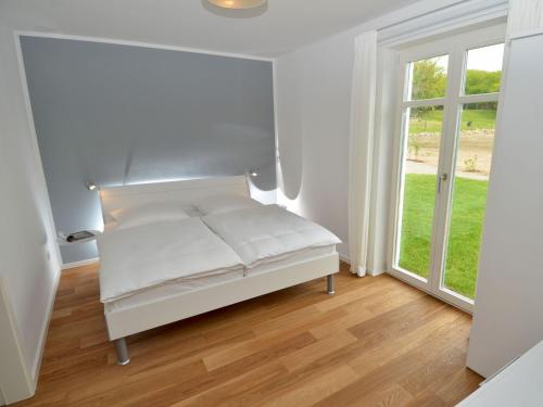 a white bed in a room with a window at Dat Dörphus am Bodden - WG 02 in Groß Zicker