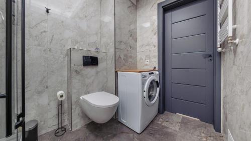 a bathroom with a toilet and a washing machine at Apartamenty Sun & Snow Kaszubska Bryza ll in Hel