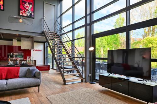 ein Wohnzimmer mit einem TV und einer Wendeltreppe in der Unterkunft Incroyable Villa 5 étoiles 7 minutes du Centre de Lille in Marcq-en-Baroeul