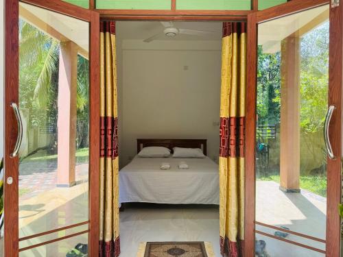 Schlafzimmer mit einem Bett durch eine Glastür in der Unterkunft Sri Ratnadeepa villa in Tissamaharama