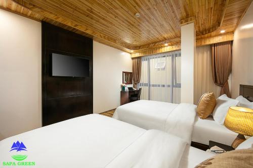 a hotel room with two beds and a flat screen tv at Sapa Green Hotel in Sa Pa