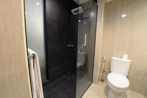 a bathroom with a toilet and a glass shower at HORU HOTEL MANGGA DUA SQUARE in Jakarta