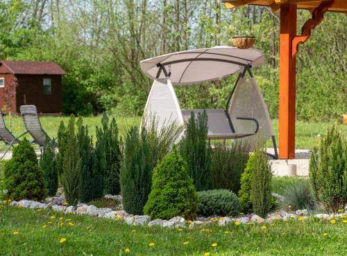 a garden with a chair under an umbrella at Robinzonski Kamp Hofman in Varaždin