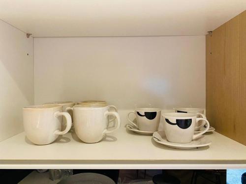 four coffee cups and saucers sitting on a shelf at Spacious 2BR APT Near Sandton City -No Loadshedding in Johannesburg