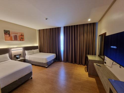 a hotel room with two beds and a flat screen tv at Altori Park Hotel in General Santos