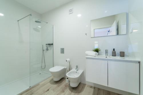 a white bathroom with a toilet and a shower at Apartment Nascer do Sol in Aljezur