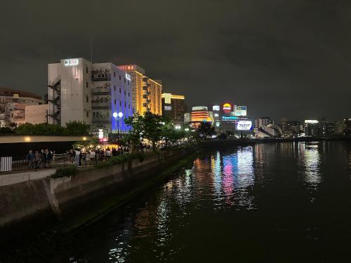 a city at night with a river and buildings at FukuokaKoryou GuestHouse in Fukuoka