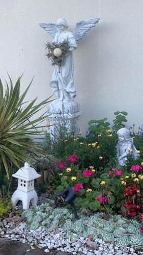a garden with an angel statue and flowers at Natthakan Heights in Te Kuiti