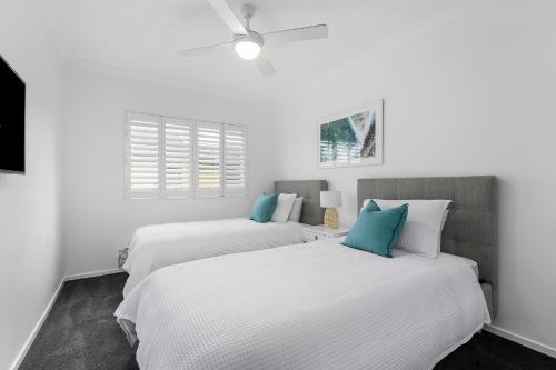 two beds in a room with white walls and blue pillows at Splendido Resort Apartments in Gold Coast