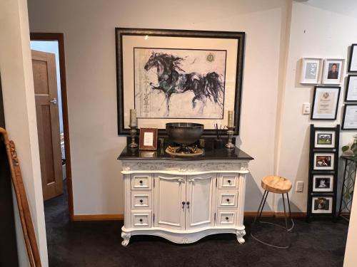 a white dresser with a painting of a horse on it at Gorgeous Villa, 7 minutes from Airport in Christchurch