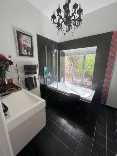a bathroom with a tub and a sink and a window at Gorgeous Villa, 7 minutes from Airport in Christchurch