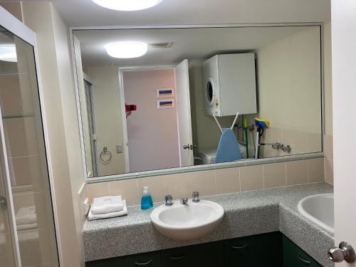 a bathroom with a sink and a large mirror at Kings Bay Apartments in Caloundra