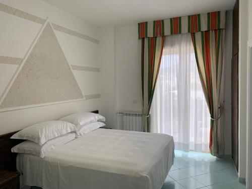 een slaapkamer met een wit bed en een raam bij Hotel Conte in Ischia