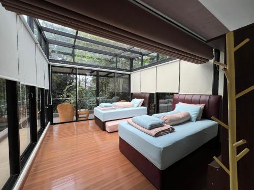 two beds in a room with glass windows at Villa Ophelia at Vimala Hills in Bogor
