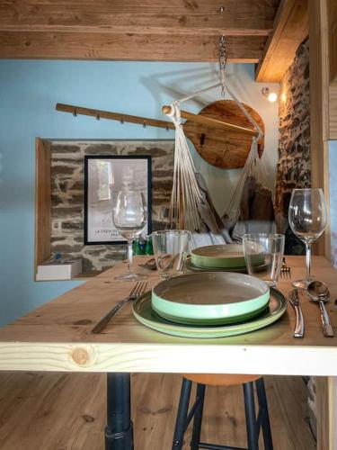 een houten tafel met borden en wijnglazen erop bij Le Four' Nid in La Terrasse-sur-Dorlay