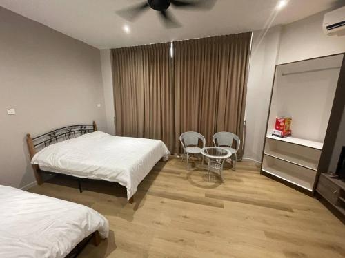 a bedroom with two beds and a table and chairs at Homestay KNK in Tawau