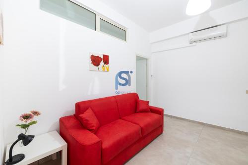 a red couch in a room with a white wall at Al Posto Giusto - Self Check in in Cefalù