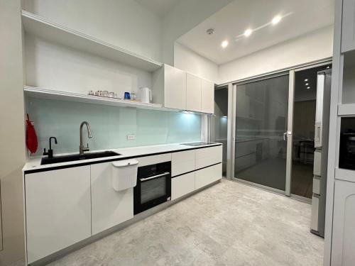 a white kitchen with a sink and a dishwasher at 隨緣居民宿 in Zhongpu