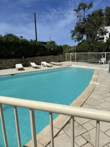 une piscine bleue avec des chaises et une clôture dans l'établissement Le Rocher - Appt pour 6 climatisé avec piscine, à LʼÎle-Rousse