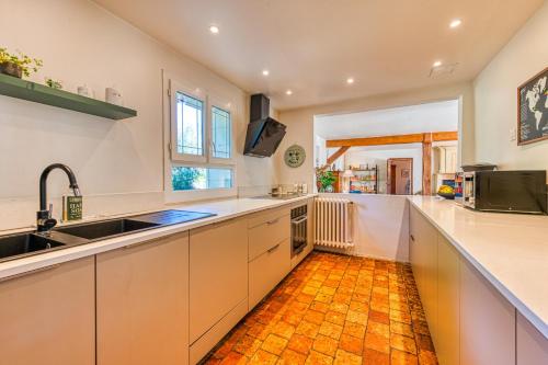 Il comprend une cuisine avec des placards blancs et du carrelage orange. dans l'établissement La Clé des Champs - Maison de charme dans un écrin de verdure, à Lierville