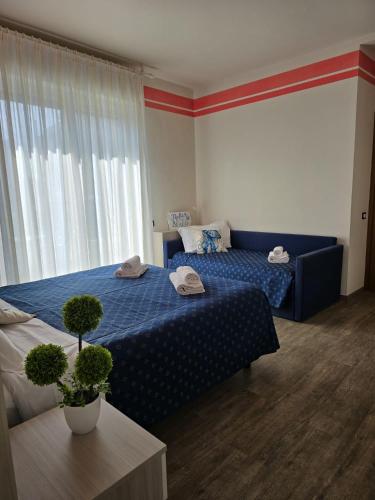 a bedroom with a blue bed and a window at Hotel Orchidea in Lignano Sabbiadoro
