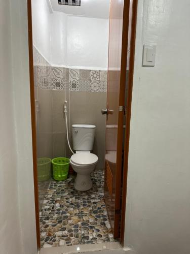 a bathroom with a toilet and a tile floor at Bearbys Homestay Siargao - C in Catangnan