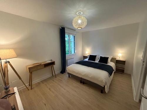 a bedroom with a bed and a table and a lamp at Le Clos des Lilas in Graves