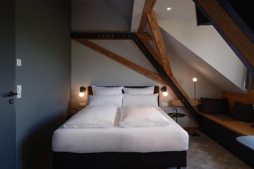 1 cama con sábanas blancas y almohadas en una habitación en Ben Hogan Lodge, en Owingen