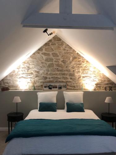 a bedroom with a large bed with a stone wall at Entre terre et mer in Ploemeur