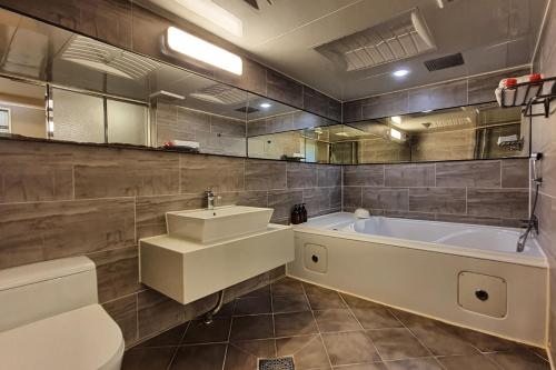 a bathroom with a tub and a sink and a toilet at Palace Hotel in Ulsan