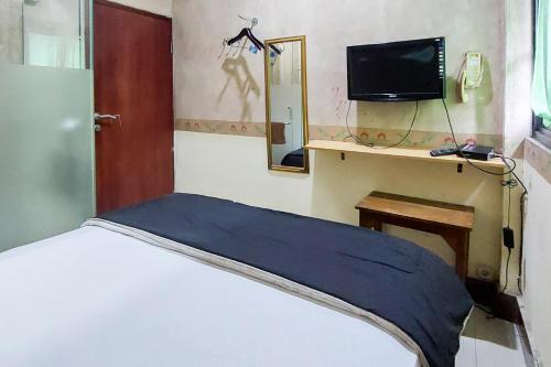 um quarto com uma cama, uma televisão e um espelho em Ni Hotel Syariah Bandara Soekarno Hatta Mitra RedDoorz em Selapajang