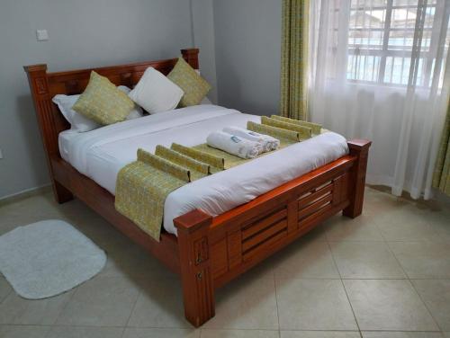 una camera con letto in legno e cuscini di JNJ luxury homes a Naivasha