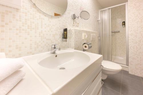 ein weißes Bad mit einem Waschbecken und einem WC in der Unterkunft Berg-Gasthof Hötzelein in Kunreuth