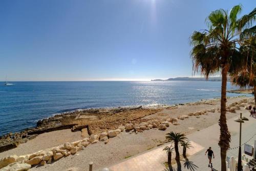 a beach with palm trees and the ocean at Apartamento en puerto de javea NYK in Jávea
