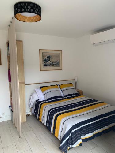 ein Schlafzimmer mit einem Bett mit einer gestreiften Decke in der Unterkunft le moulin blanc in Castelmaurou