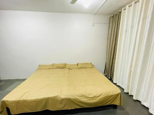 a bedroom with a bed with a yellow blanket at Tuljai Homestay in Tuljapur