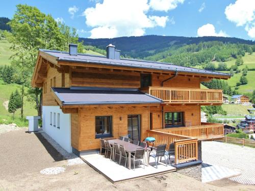 eine Blockhütte mit einem Tisch und Stühlen auf dem Deck in der Unterkunft Modern chalet with sauna near ski area in Saalbach Hinterglemm Salzburgerland in Saalbach-Hinterglemm