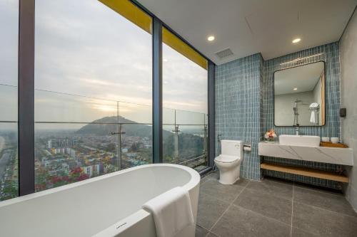 a bathroom with a tub and a toilet and a window at Flamingo Ibiza Hải Tiến in Nam Khê